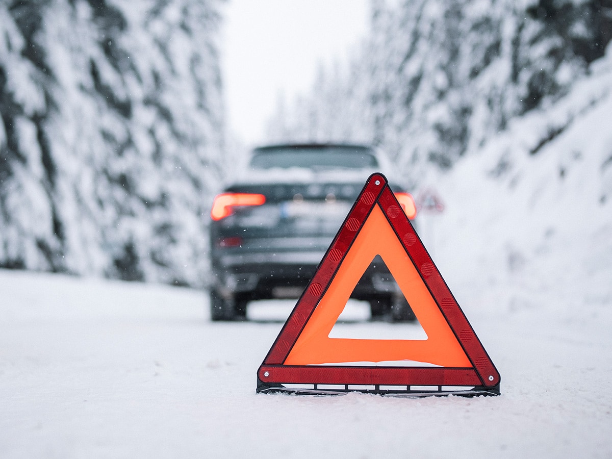 Varningstriangel bakom bil i snölandskap